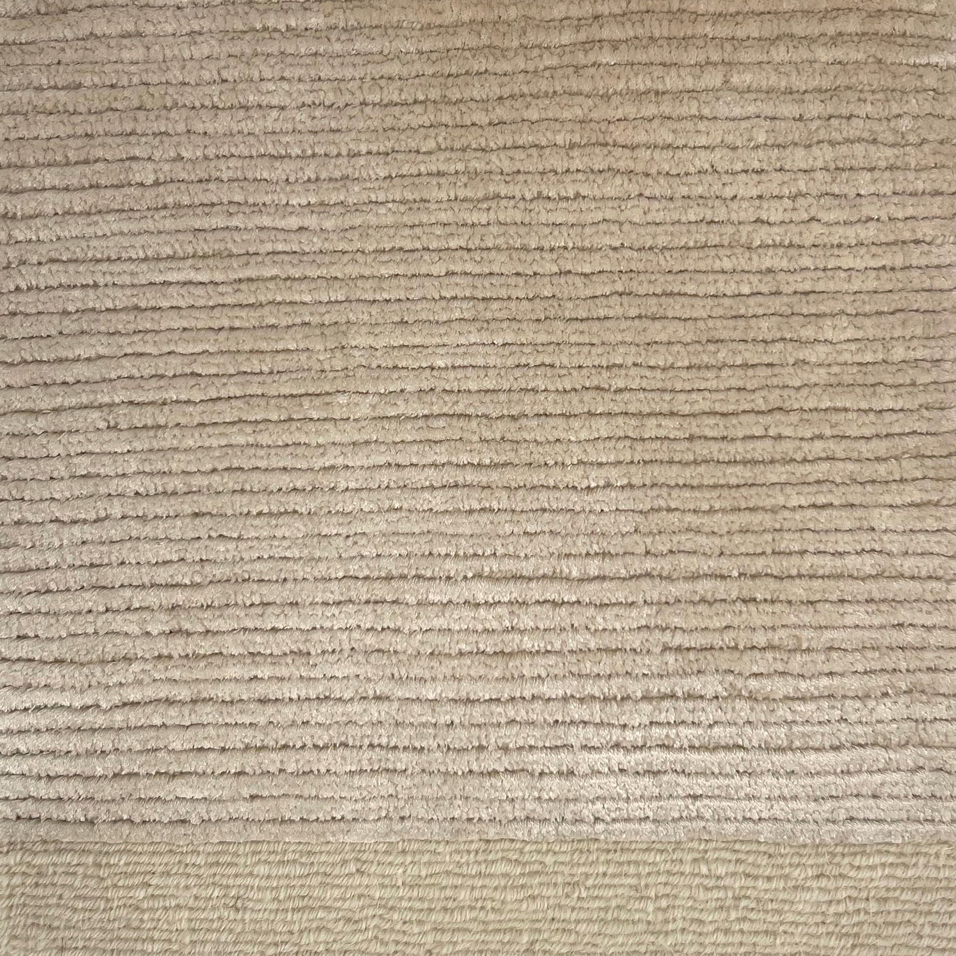 Handkotted rug in cream with a ribbed stripe design. 
