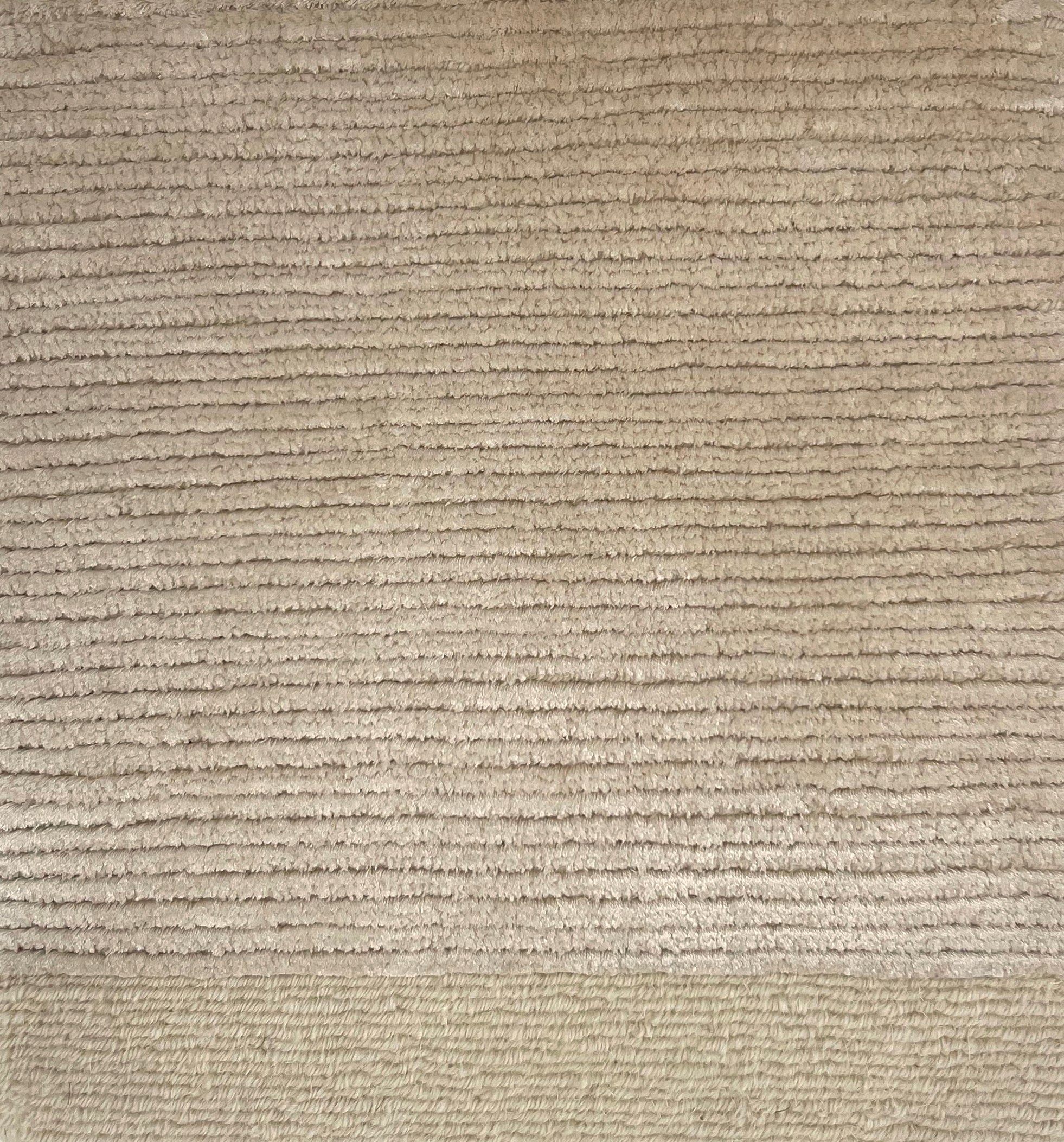 Handkotted rug in cream with a ribbed stripe design. 