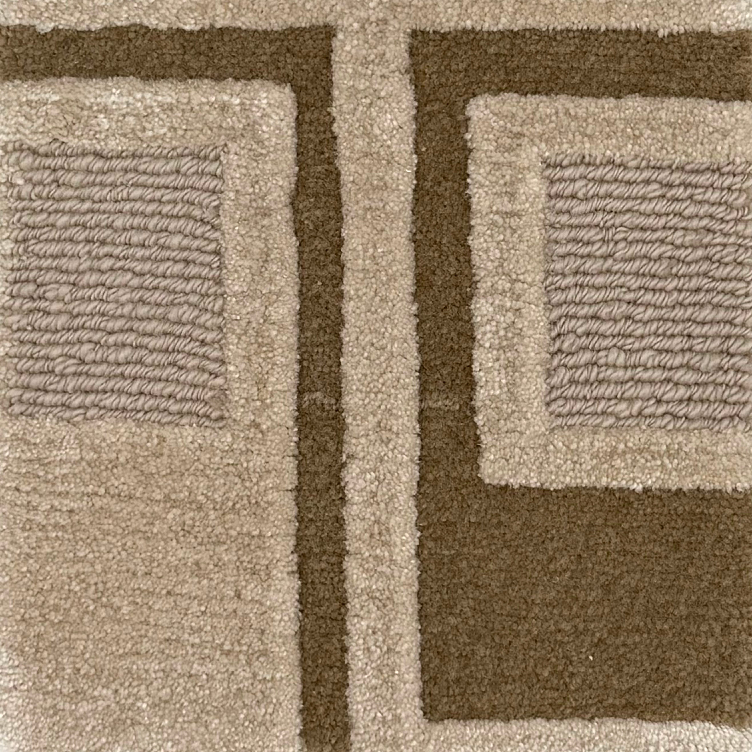 Close-up of a textured area rug with a geometric pattern in taupe, beige, and dark brown.