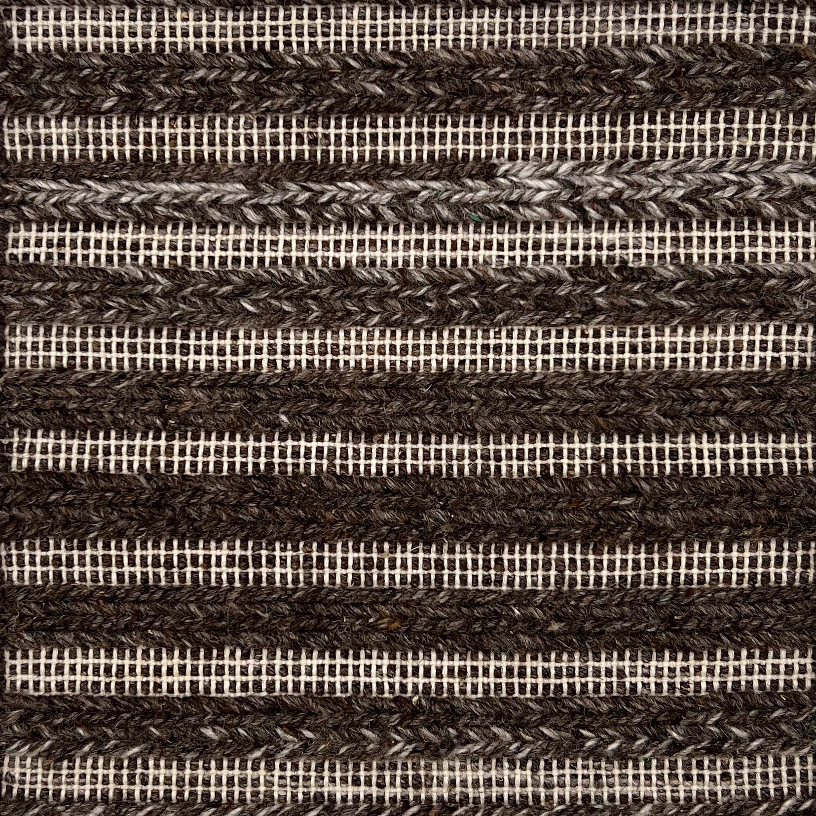 Flatweve rug with a raised brained stripe in brown on a cream textured field. 