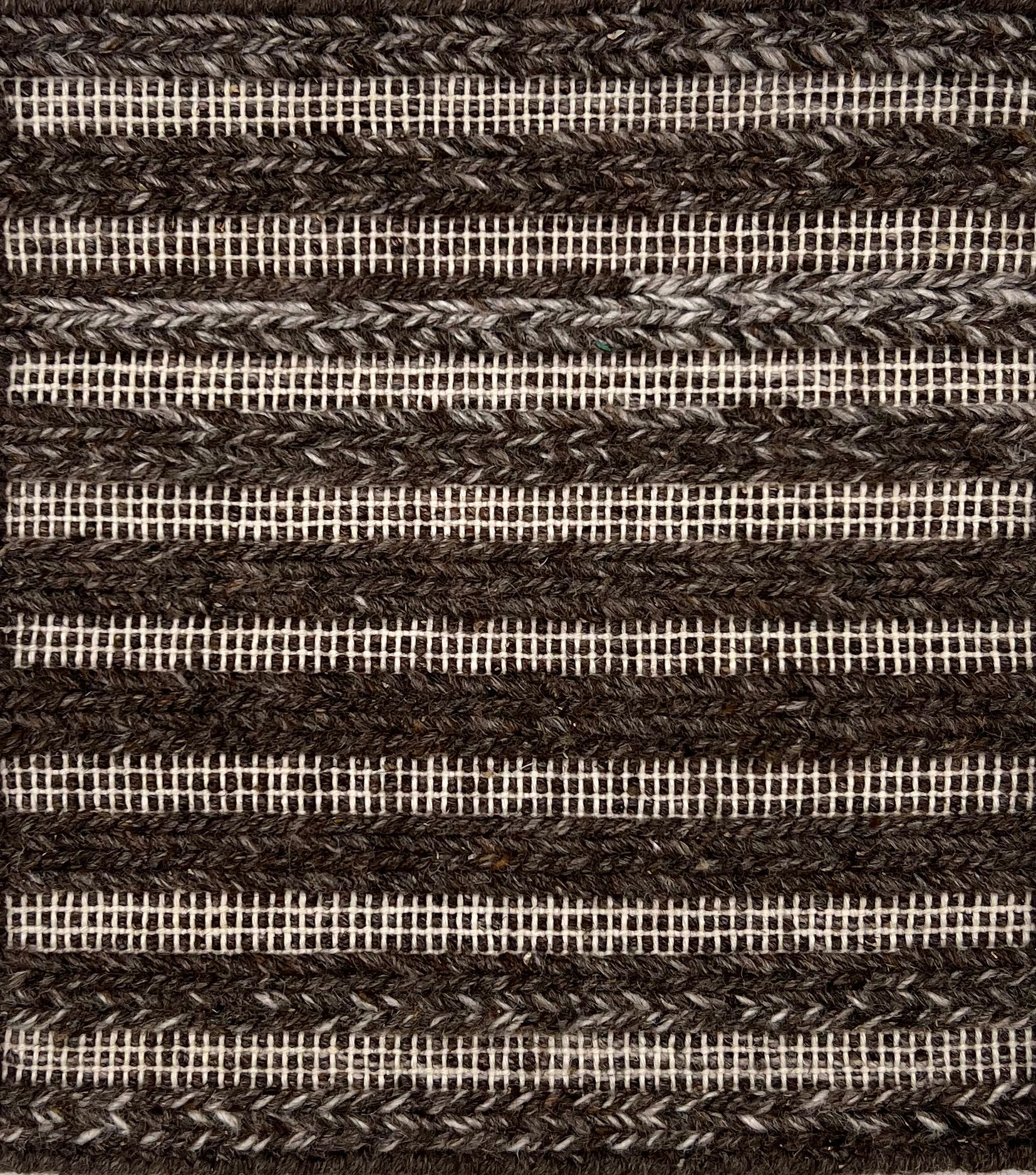 Flatweve rug with a raised brained stripe in brown on a cream textured field. 