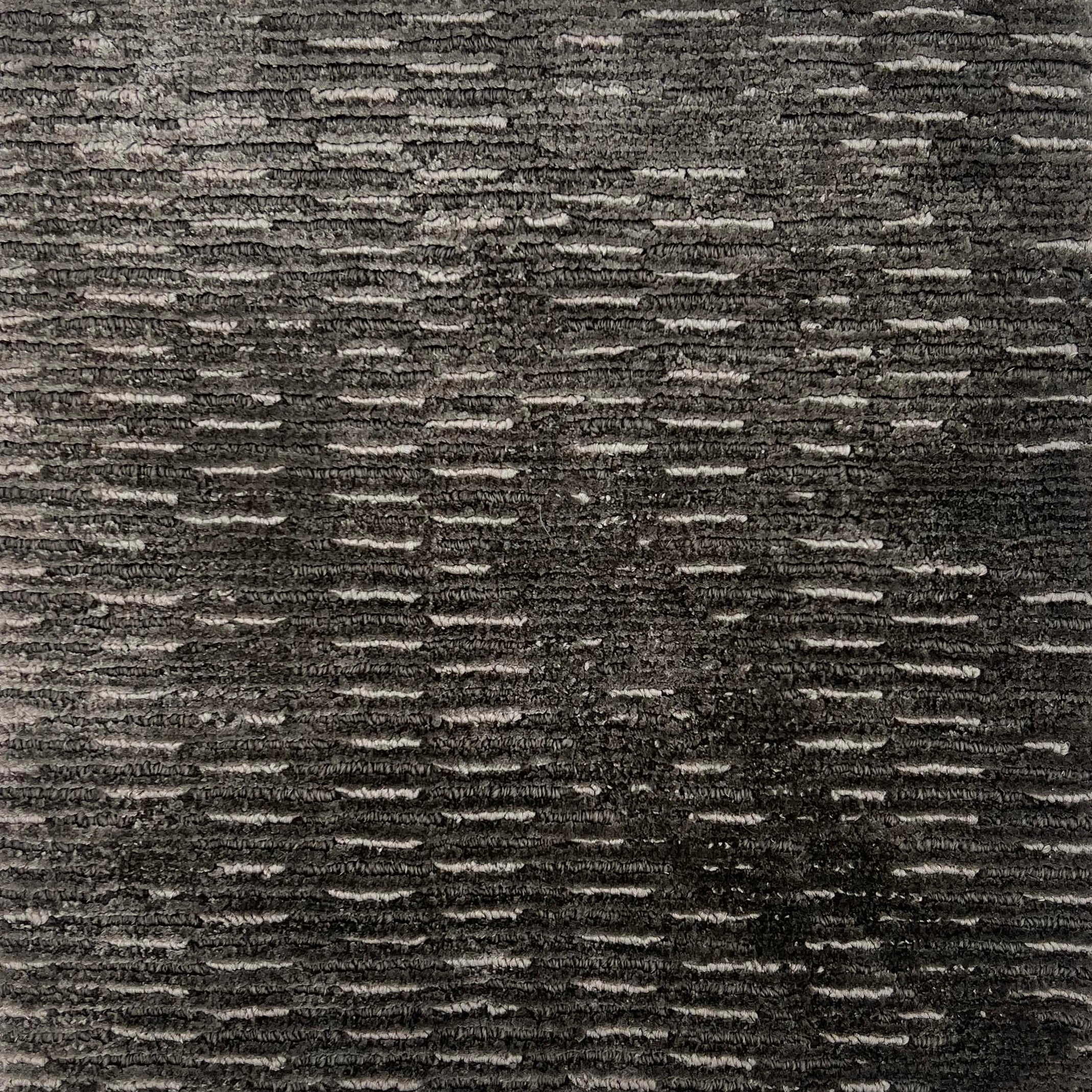 Handknitted rug in a textural linear design in shades of grey. 