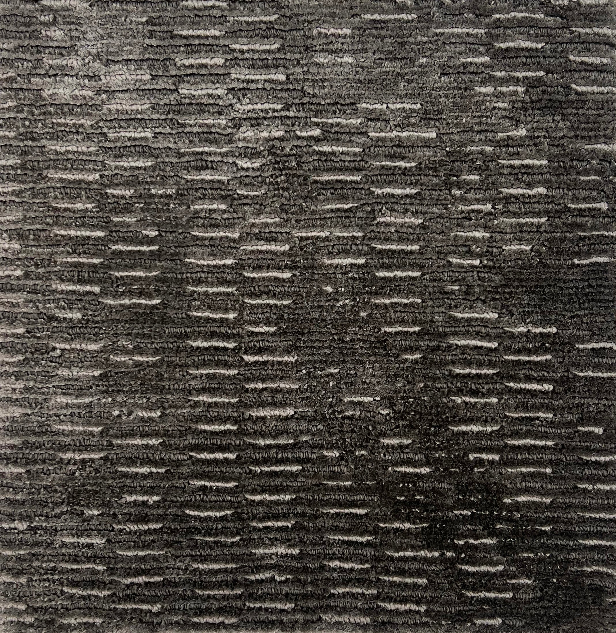 Handknitted rug in a textural linear design in shades of grey. 