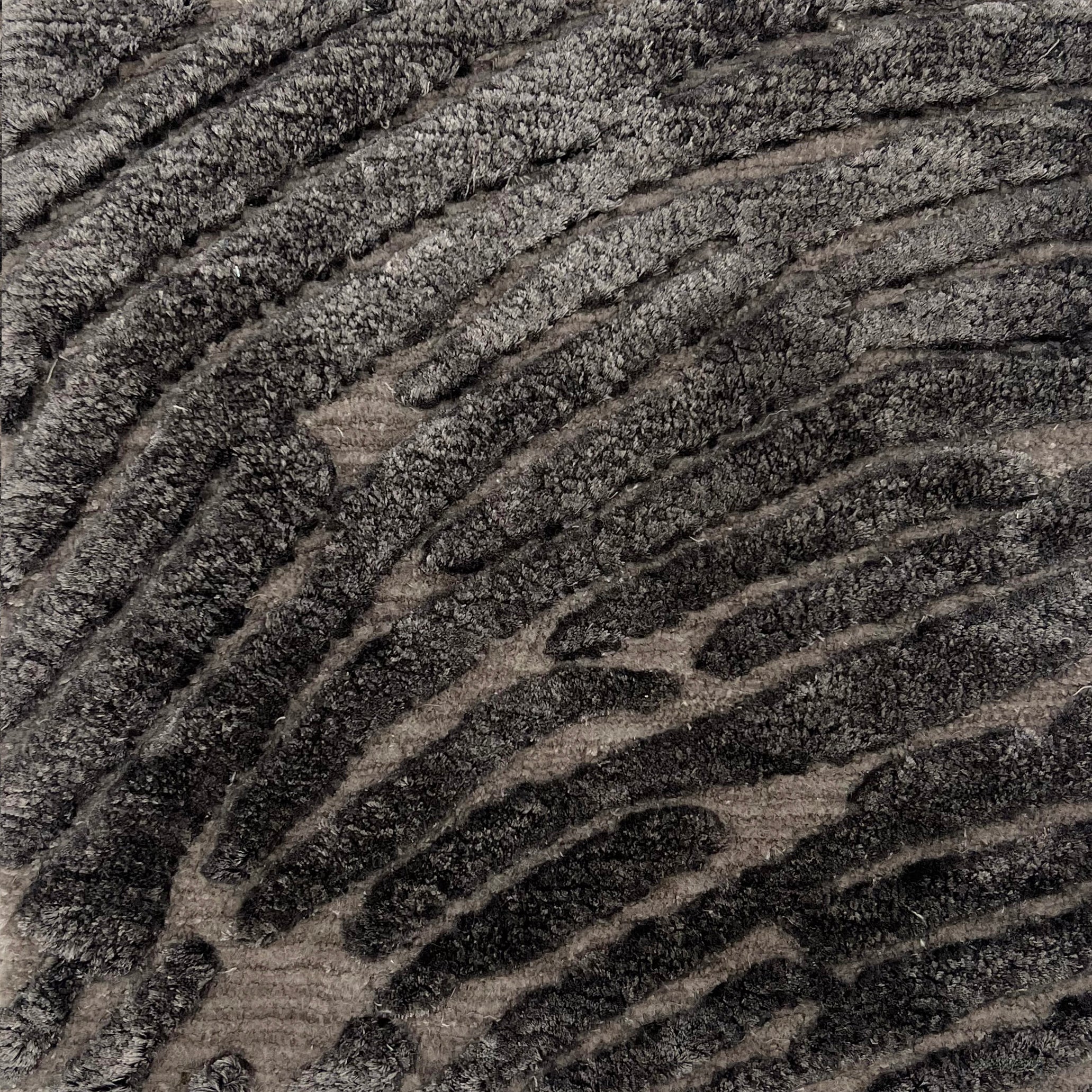 Handknotted rug with a raised abstract linear design in shades of grey. 