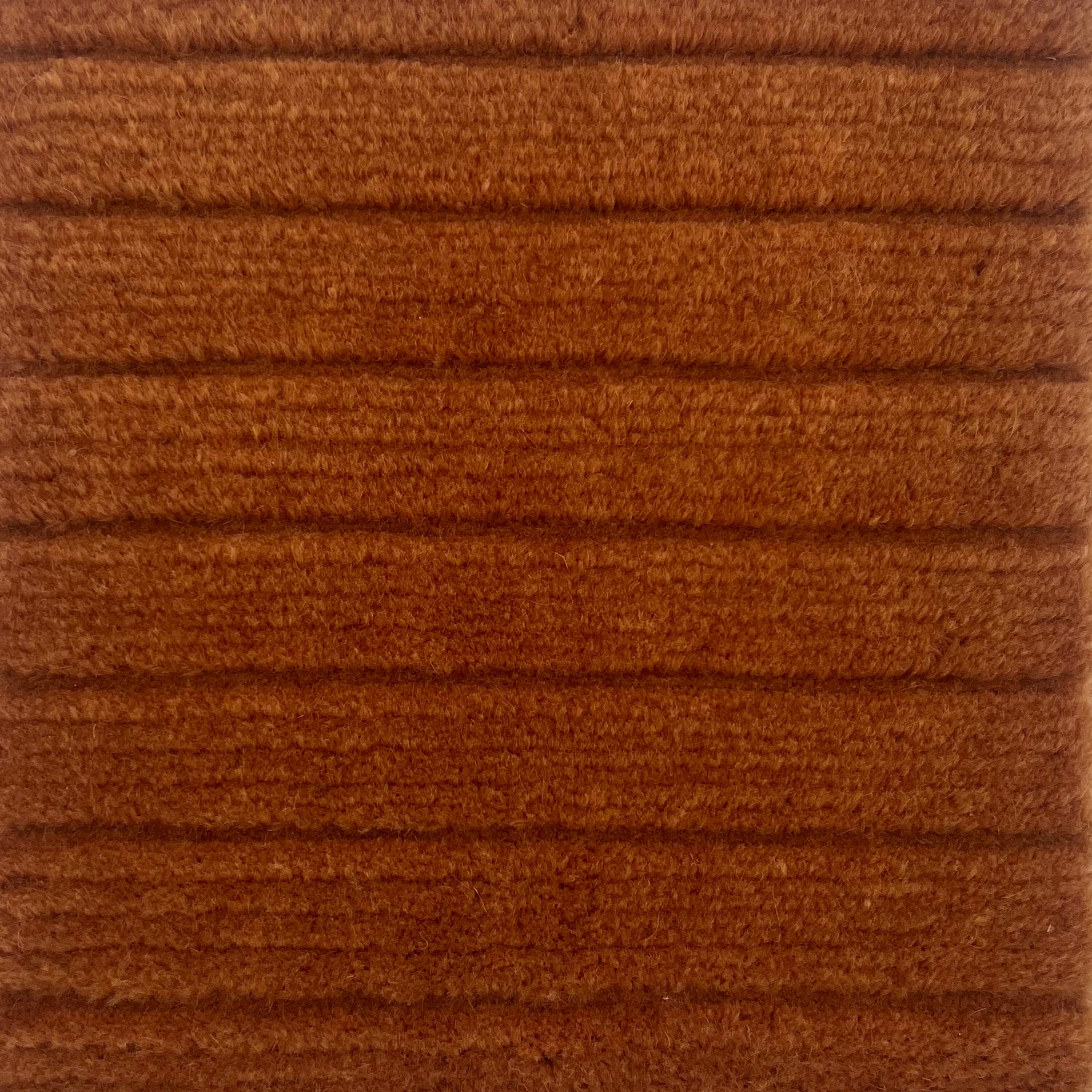 Handknotted rug in a wide raised cut pile stripe in rust wool. 