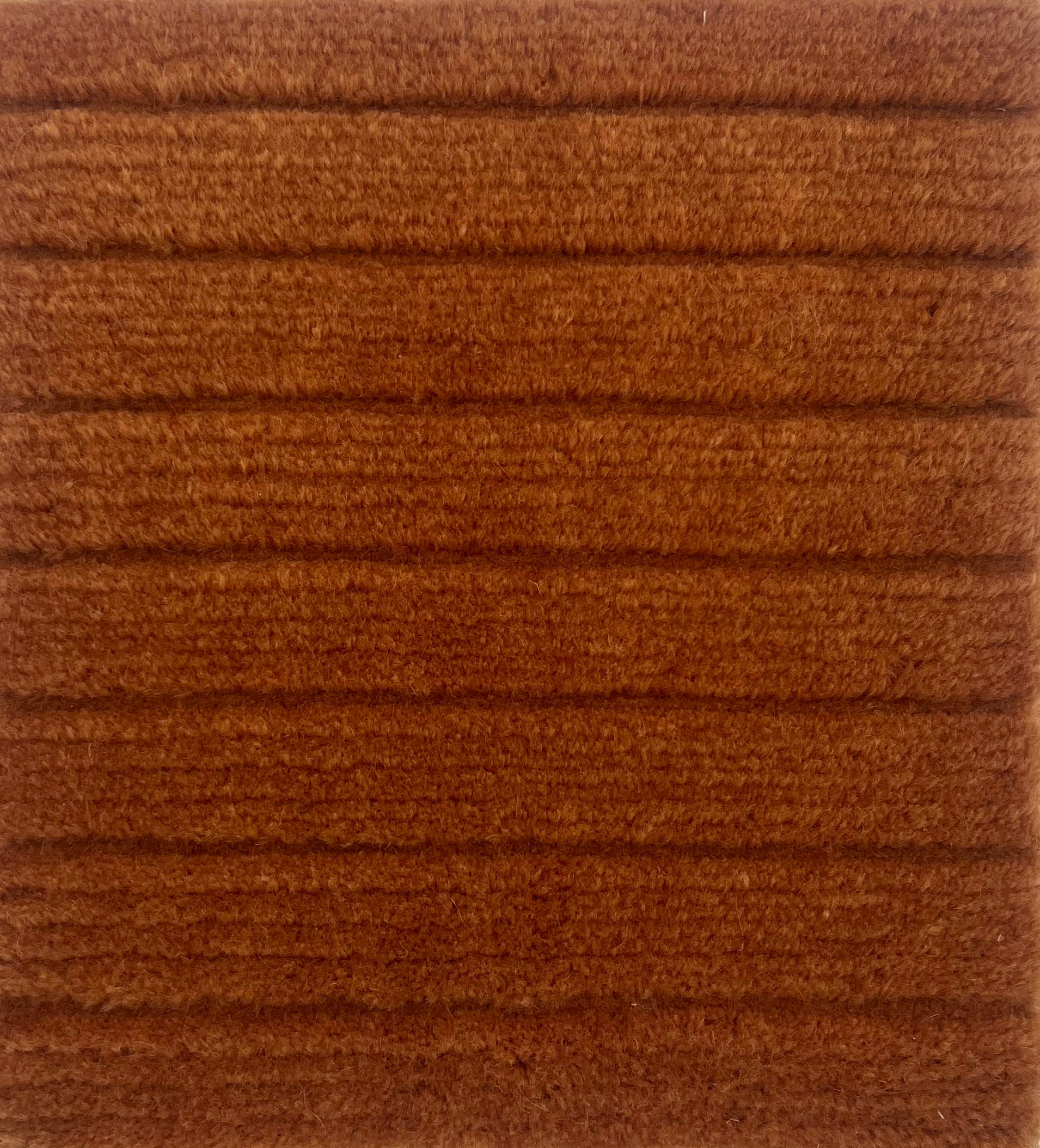 Handknotted rug in a wide raised cut pile stripe in rust wool. 