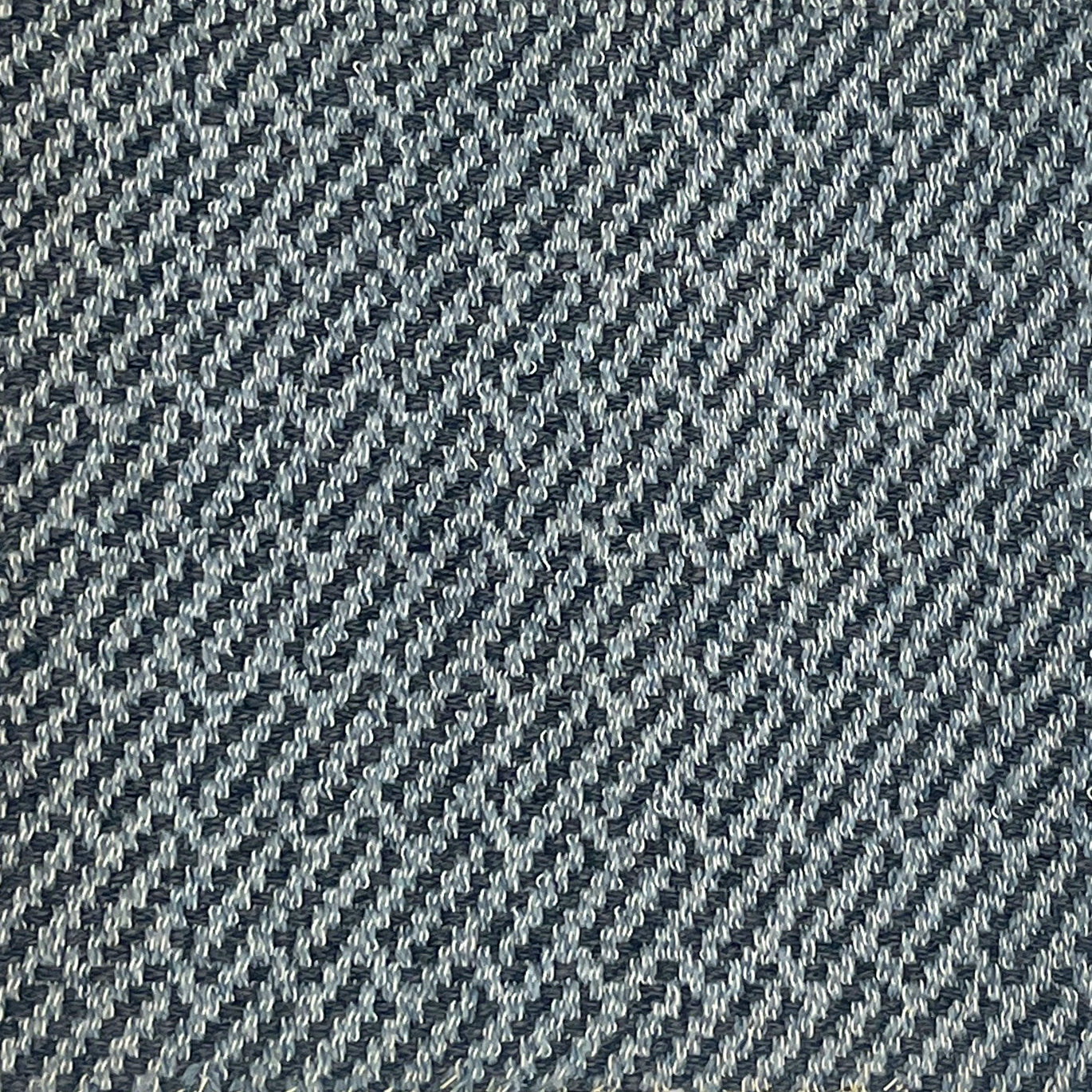 A close-up of a woven rug sample with a diagonal twill pattern in dark navy blue and light gray.