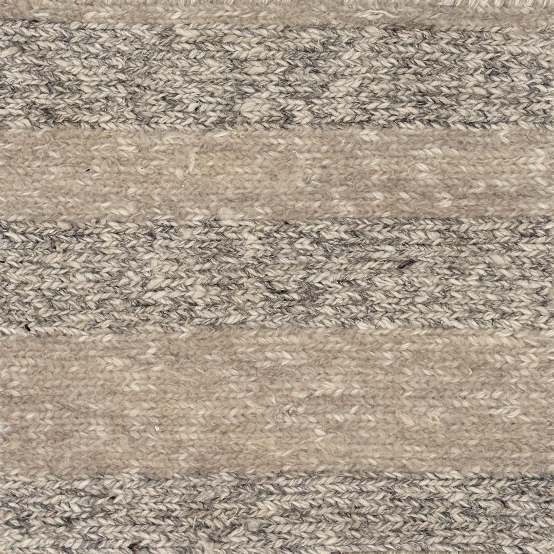 Close up of a handwoven rug in textural sumak weave with grey and beige stripes. 