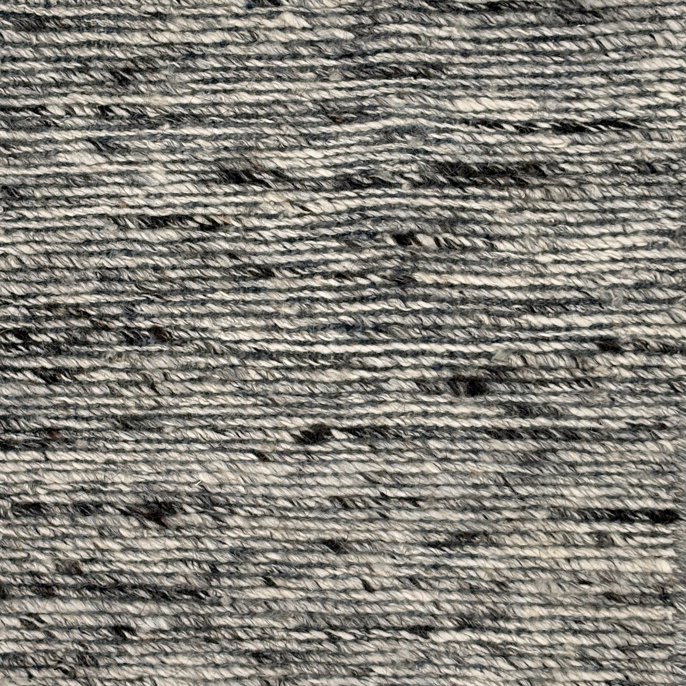 Close up of a handwoven rug in textural sumak weave in black and white marled yarn.