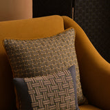 Ochre yellow couch with two embroidered throw pillows in a basketweave design in shades of green, ecru and navy. 