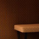Settee bench with a warm beige embroidered upholstery in tan against a wall in the same design in a darker shade of brown. 