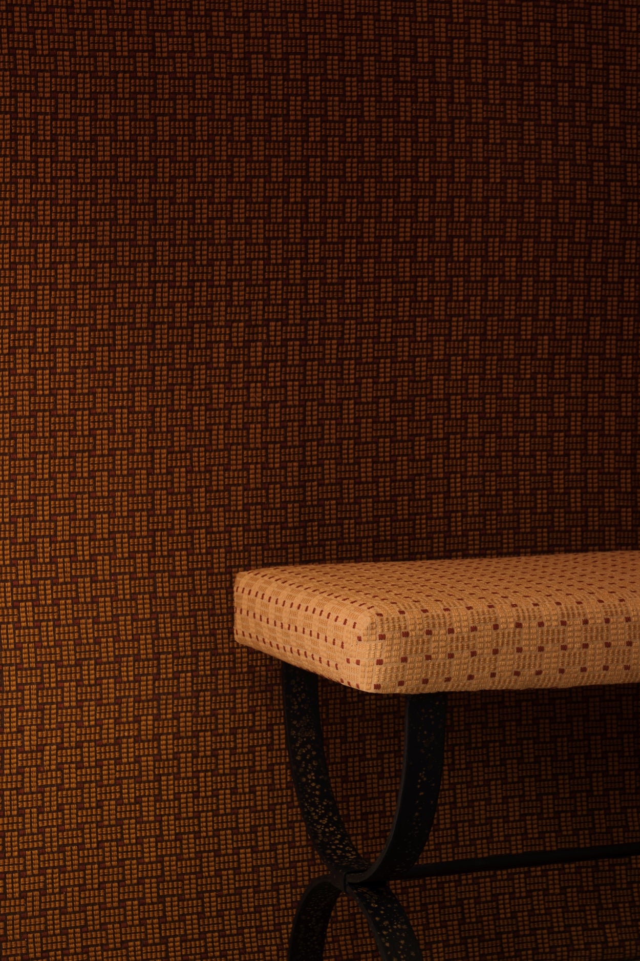 Settee bench with a warm beige embroidered upholstery in tan against a wall in the same design in a darker shade of brown. 