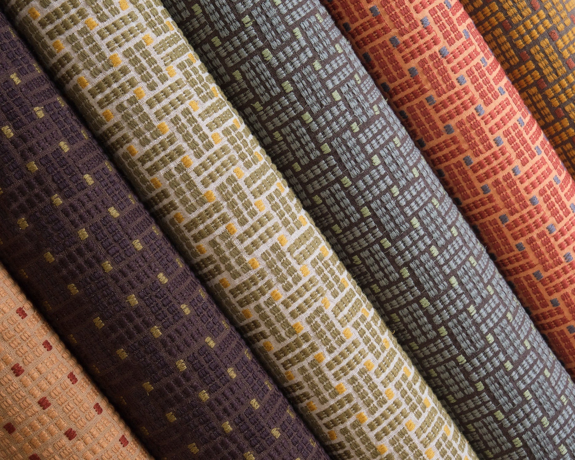 Detail image of basketweave embroidered fabrics in array of moody jewel tones.