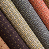 Detail image of basketweave embroidered fabrics in array of moody jewel tones.