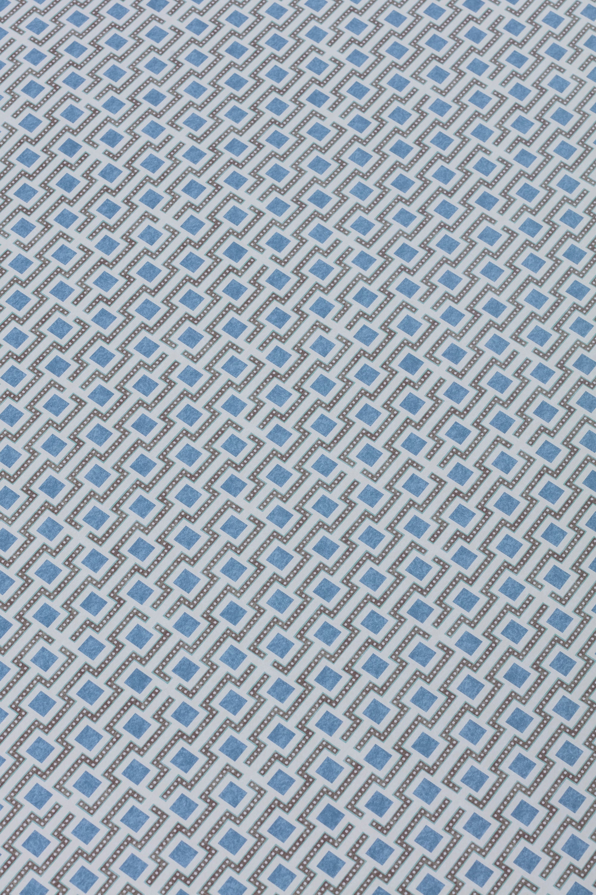 Detail of a wallpaper panel in a geometric grid print in shades of blue and gray.