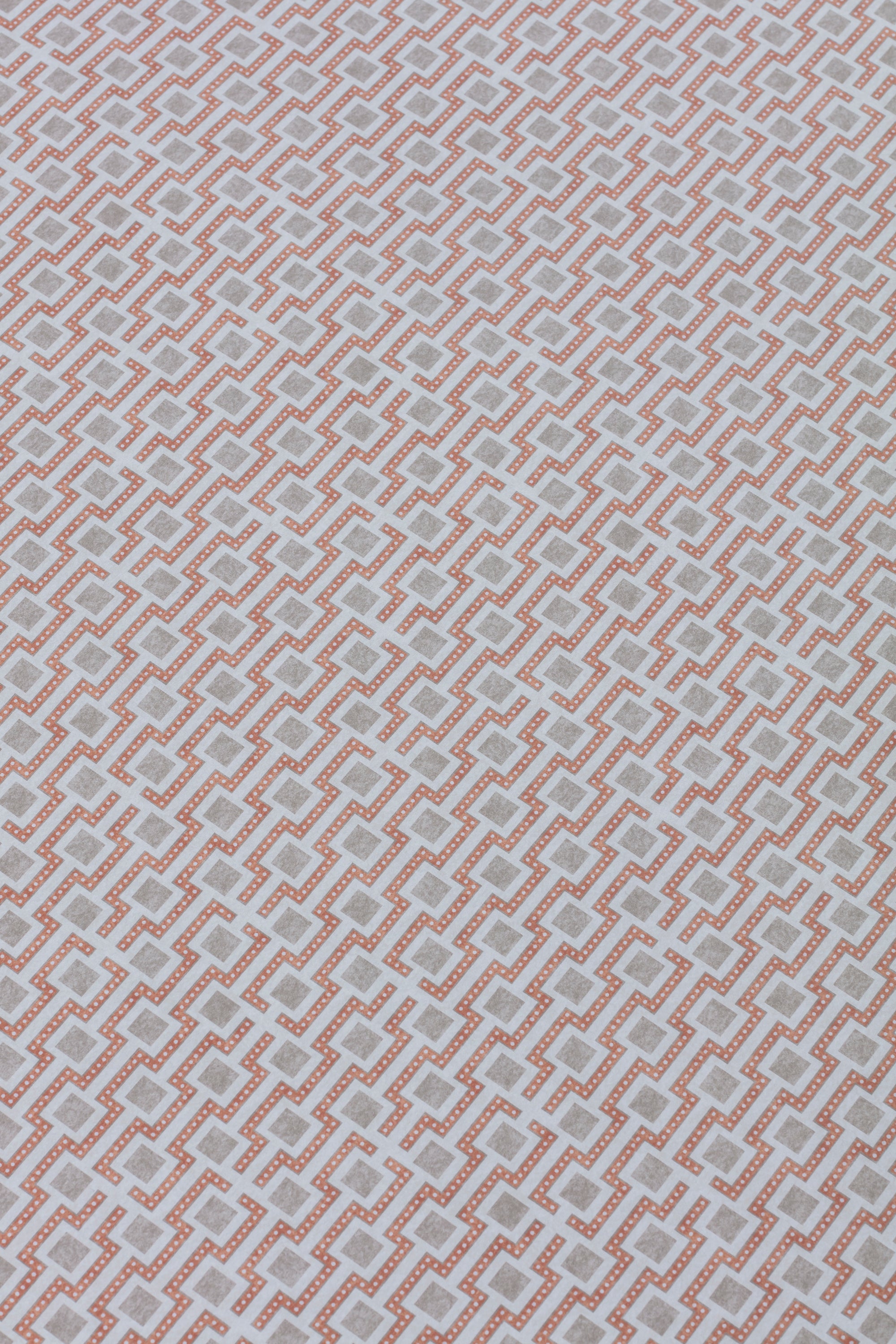 Detail of a wallpaper panel in a geometric grid print in shades of pink and gray.