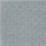 Handtufted rug sample with a repeating scallop pattern in muted blue-gray tones.