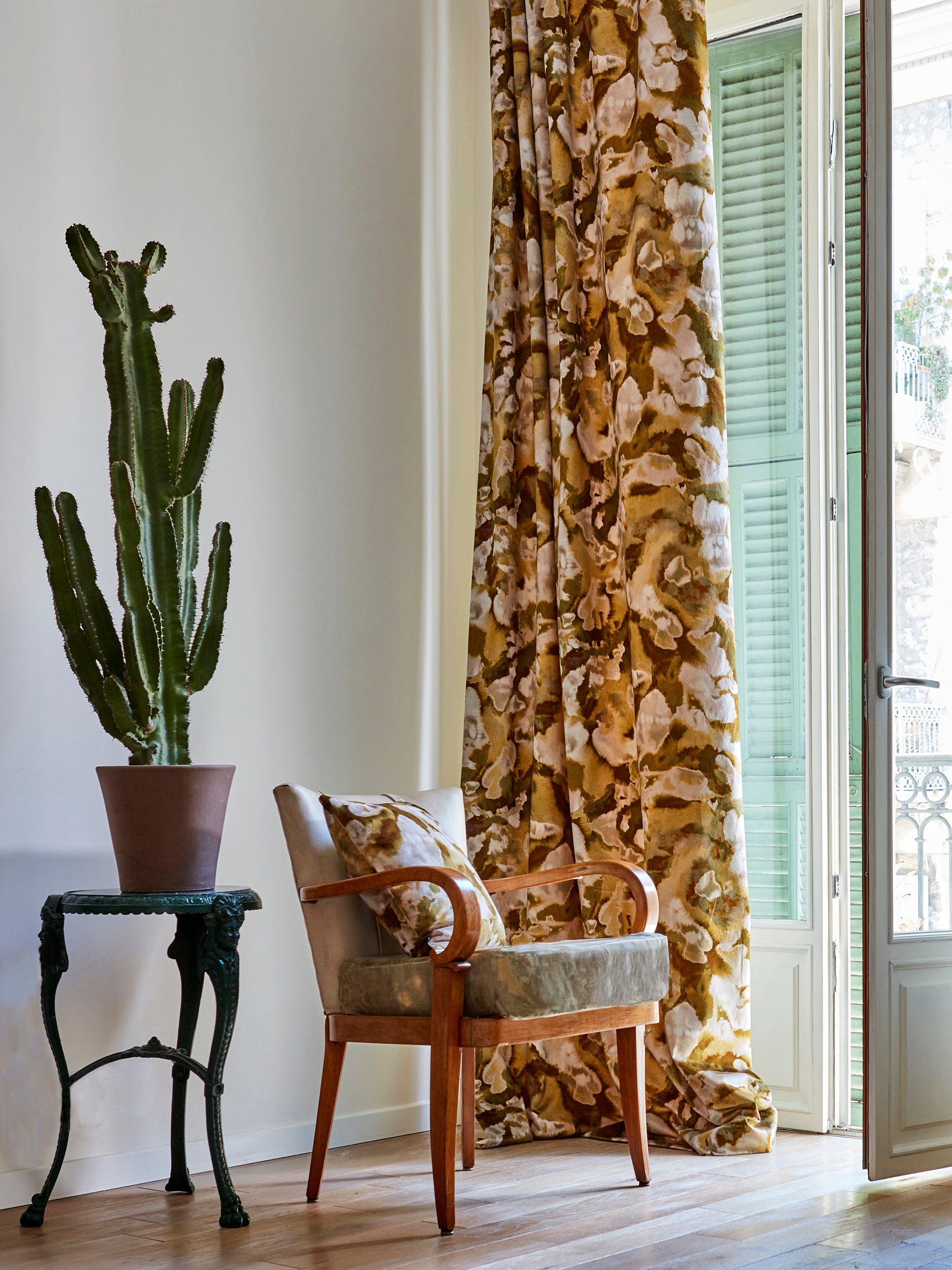 A living space with long curtains and an armchair, both in the same abstract brown and cream paint print.