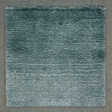 Handloomed rug with tonal border and raised cut pile shag field in soft teal.