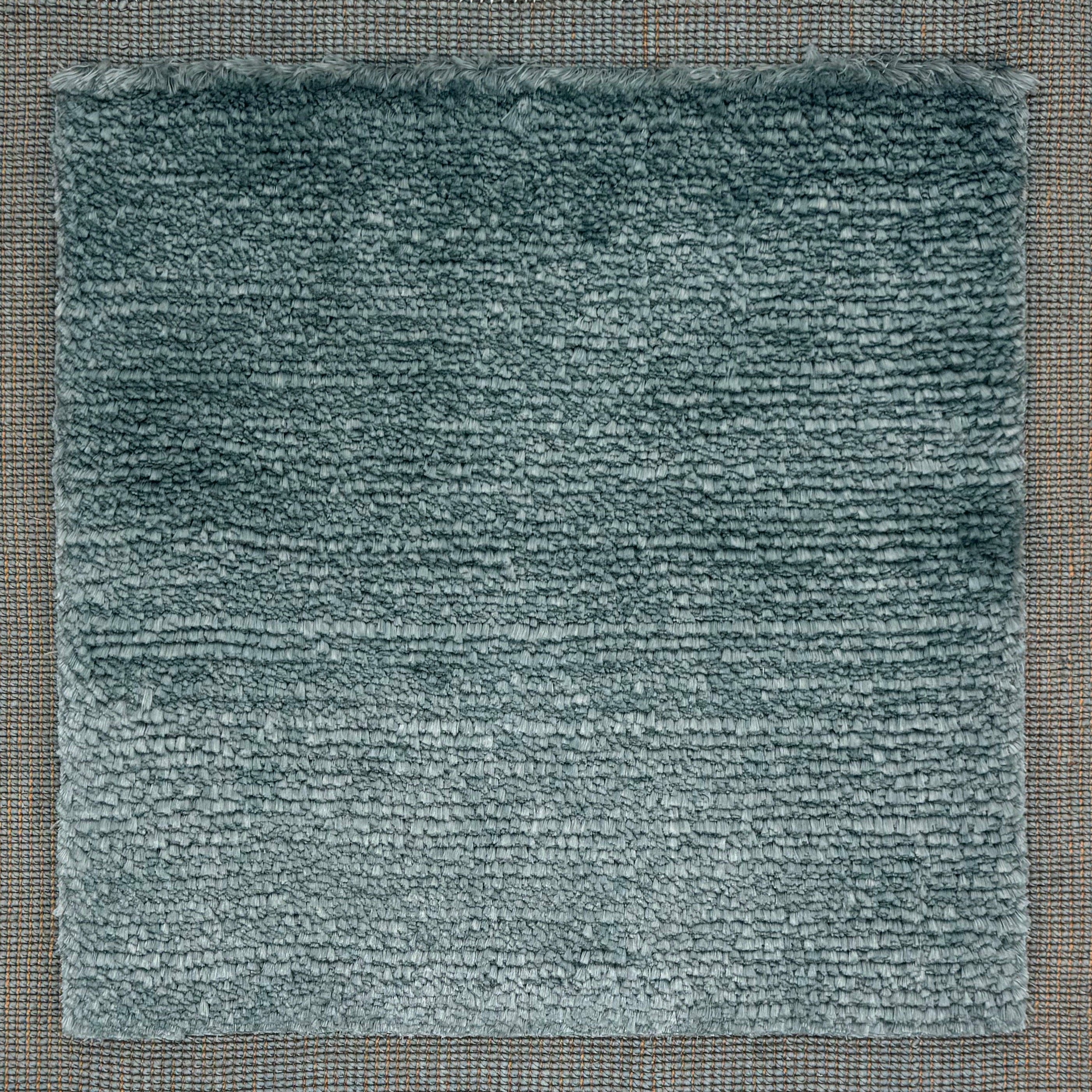 Handloomed rug with tonal border and raised cut pile shag field in soft teal.
