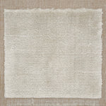Handloomed rug with neutral border and raised cut pile shag field in cream.