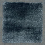 Handloomed rug with tonall border and raised cut pile shag field in dark blue.