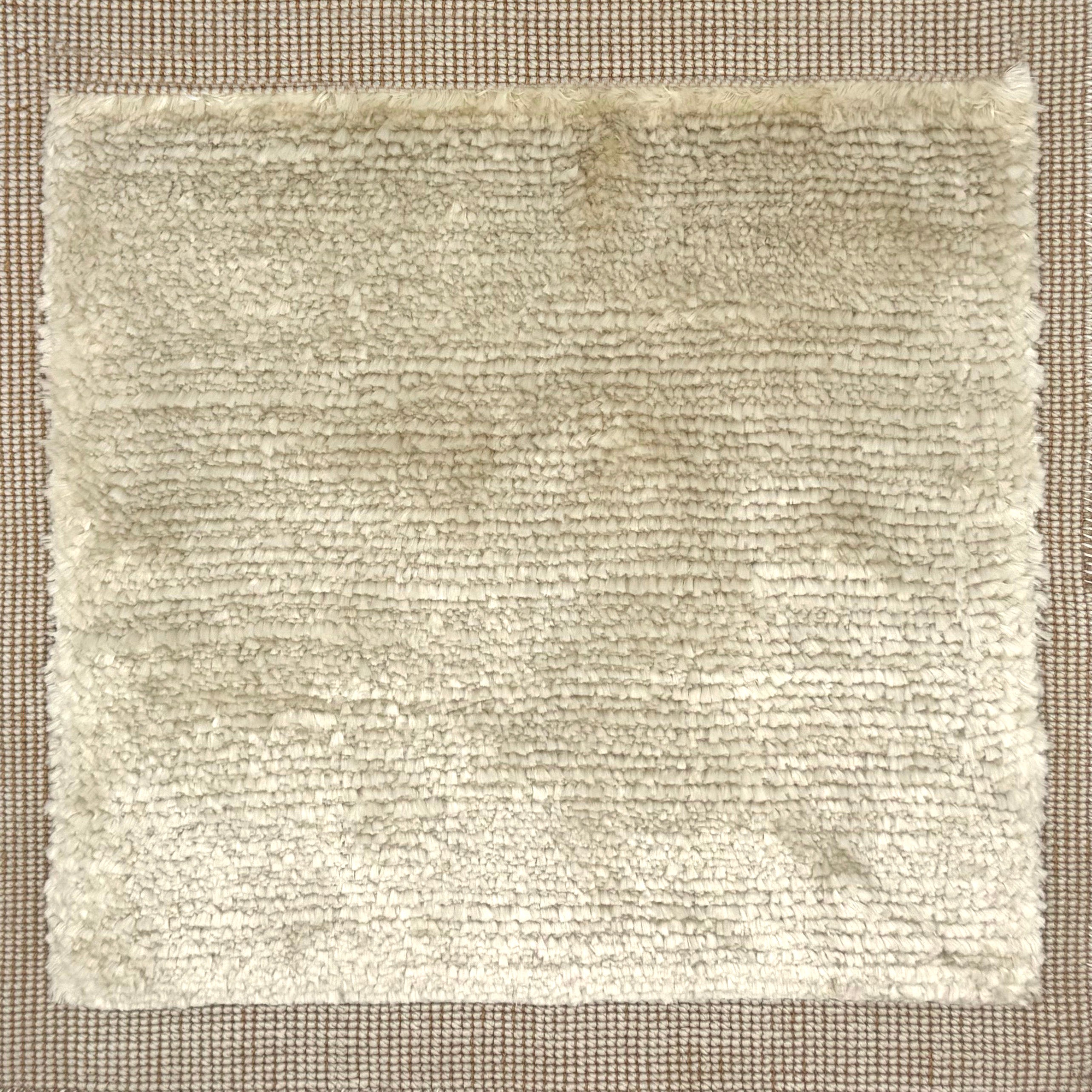 Handloomed rug with neutral border and raised cut pile shag field in beige.