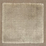 Handloomed rug with neutral border and raised cut pile shag field in taupe. 