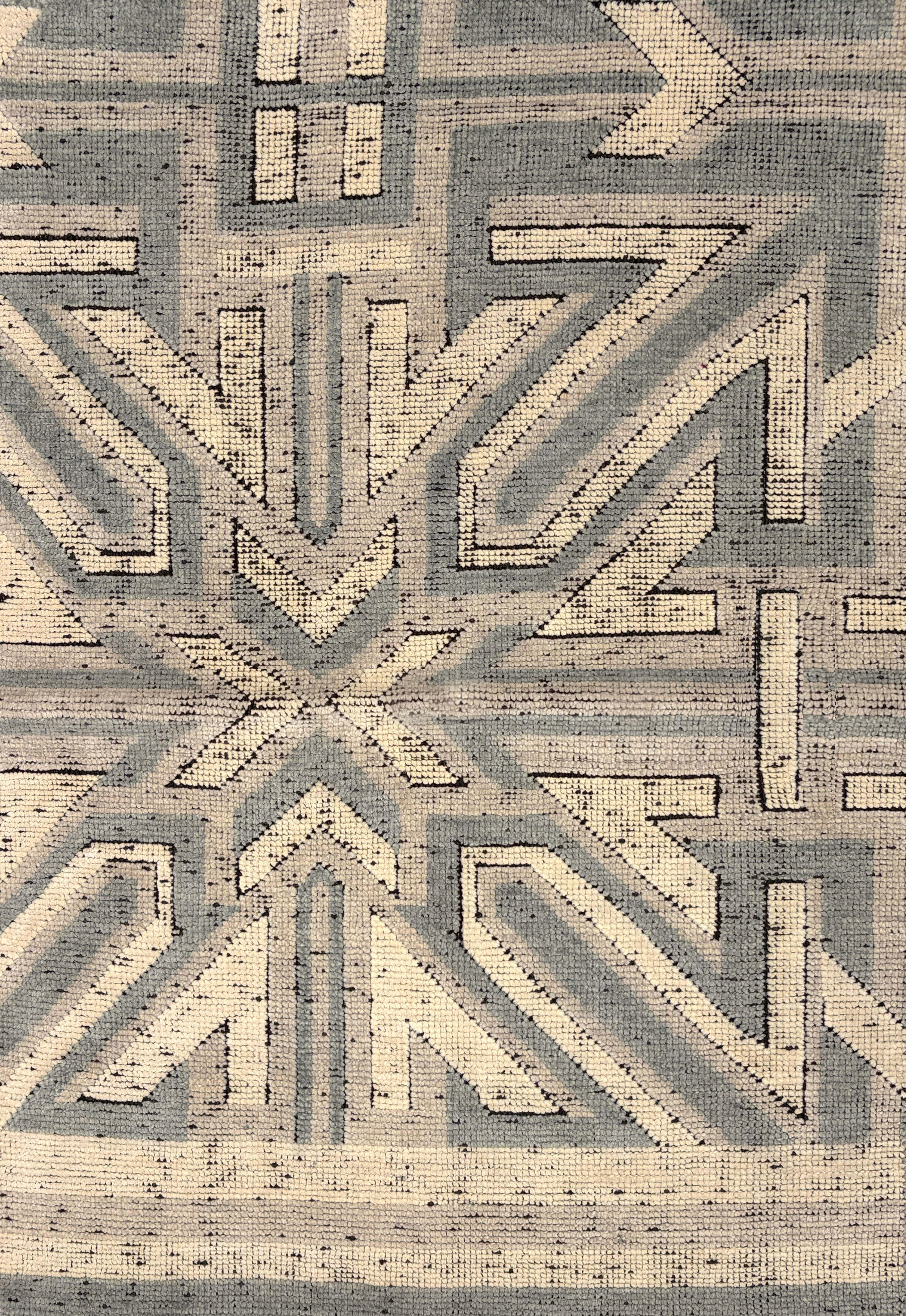 Geometric patterned rug with arrows in gray and beige tones