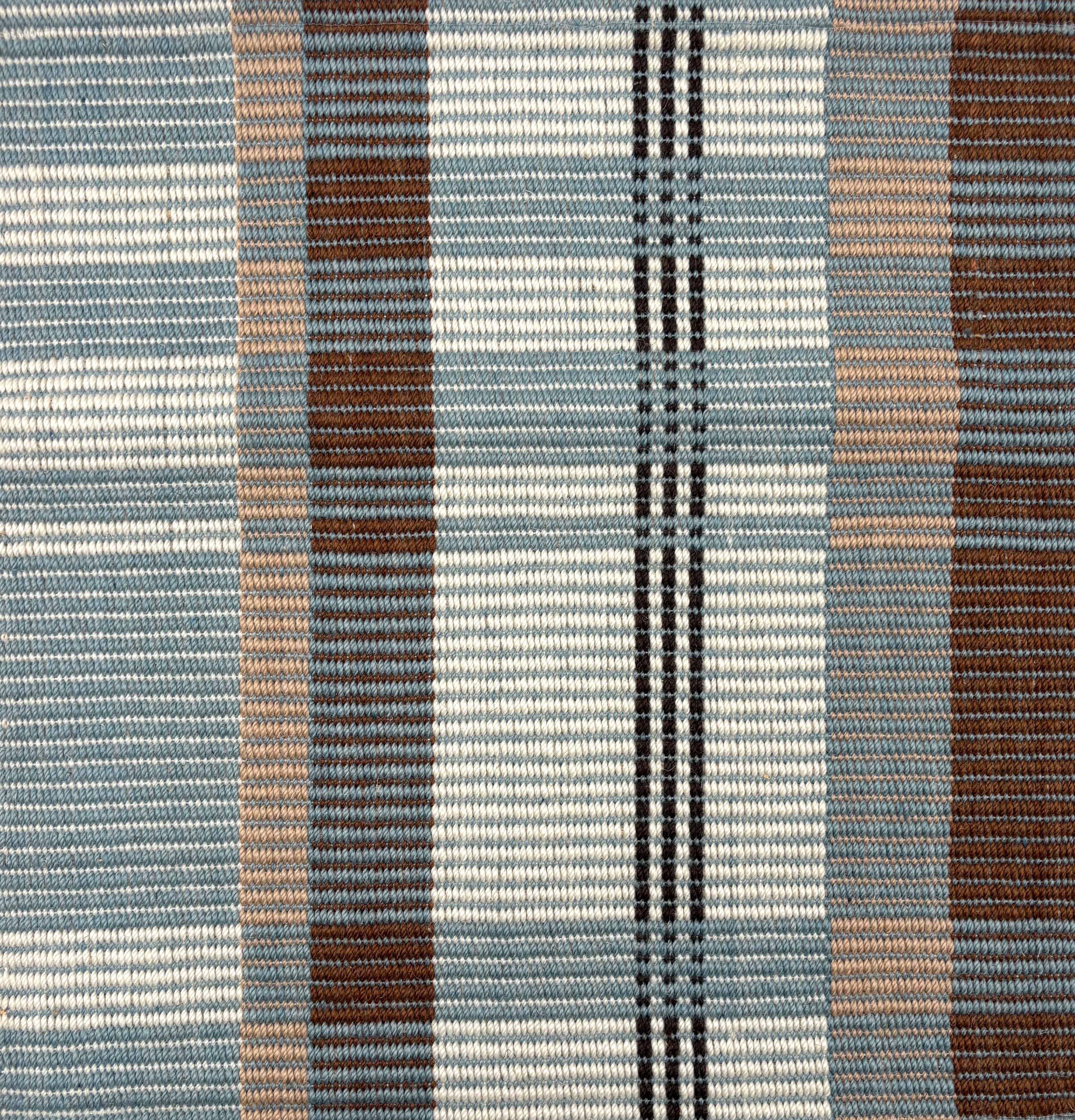 Handwoven rug in a large scale plaid in shades of teal, brown, tan, cream and black. 