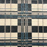 Handwoven rug in a bold windowpane plaid pattern in black, white, grey and blue. 