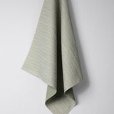 Draped woven outdoor fabric in a subtle check design in green on a white wall. 