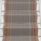 Striped flatweave runner in grey with pink orange and tan on white staircase