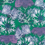 Detail of wallpaper in a dense floral print in shades of cream, purple and green on a green field.
