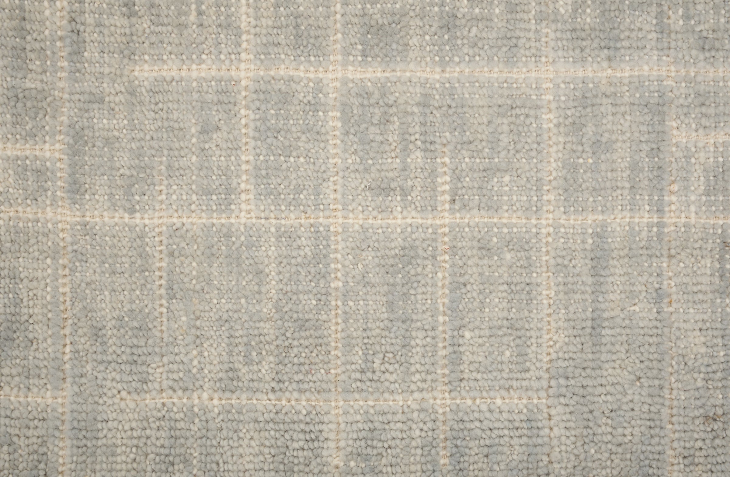 Textured carpet with a checkered pattern in gray and beige tones.