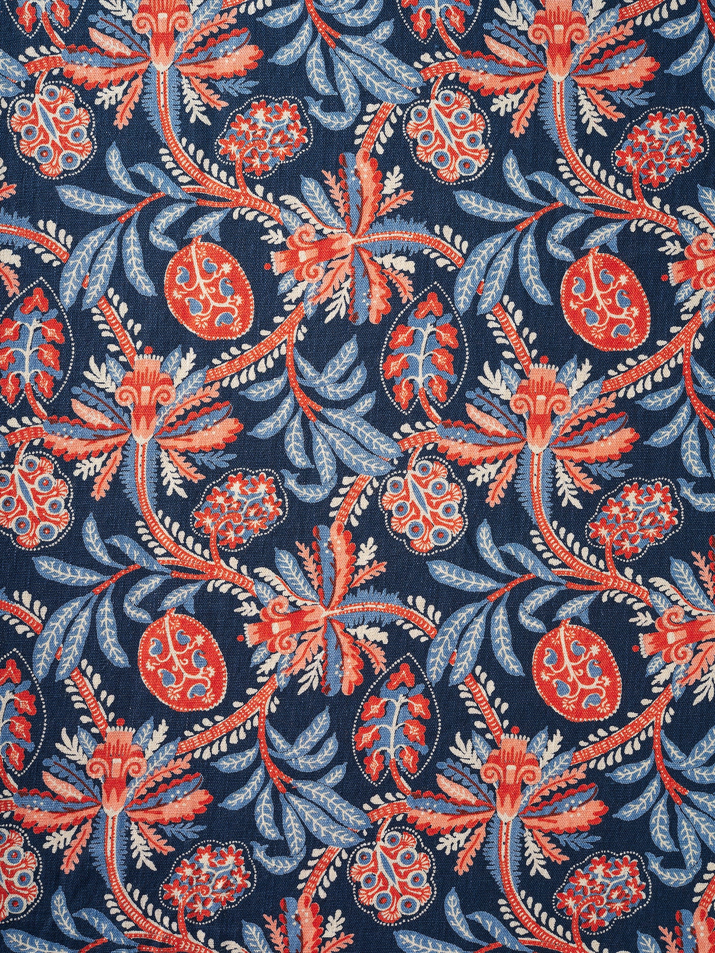 A close-up of a fabric pattern featuring stylized botanical motifs with coral-red and light blue flowers and leaves on a dark navy blue background.