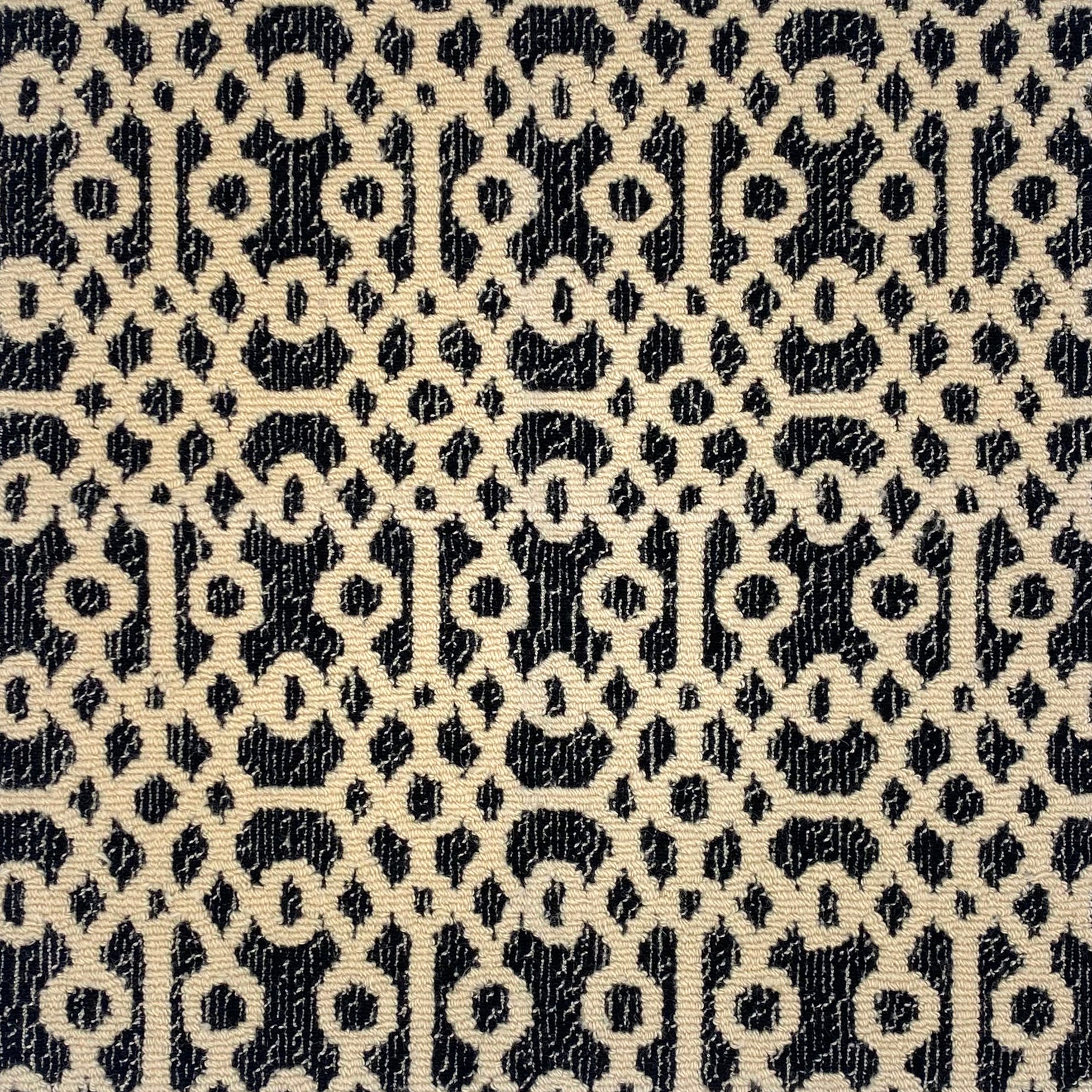 Handtufted rug with ornate filigree pattern in creme on a heathered black field. 