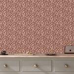 Patterned wallpaper with a pink and brown design on a wall above a wooden dresser.
