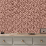 Patterned wallpaper with a pink and brown design on a wall above a wooden dresser.