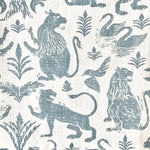 Close-up of fabric in a lion and plant print in blue-gray on a white field.