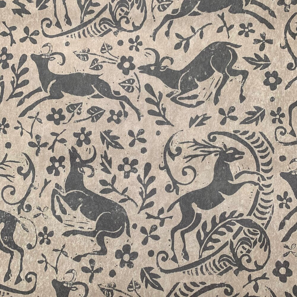 Detail of wallpaper in a deer, leaf and flower print in gray on a mottled tan field.