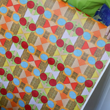 Detail of a woman holding a wallpaper with a collaged circle, square and diamond stripe wallpaper in red, orange, green and pink. 