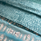 Stack of folded fabric swatches in various patterns in shades of blue