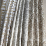 Stack of folded fabric swatches in various patterns in a soft neutral palette. 
