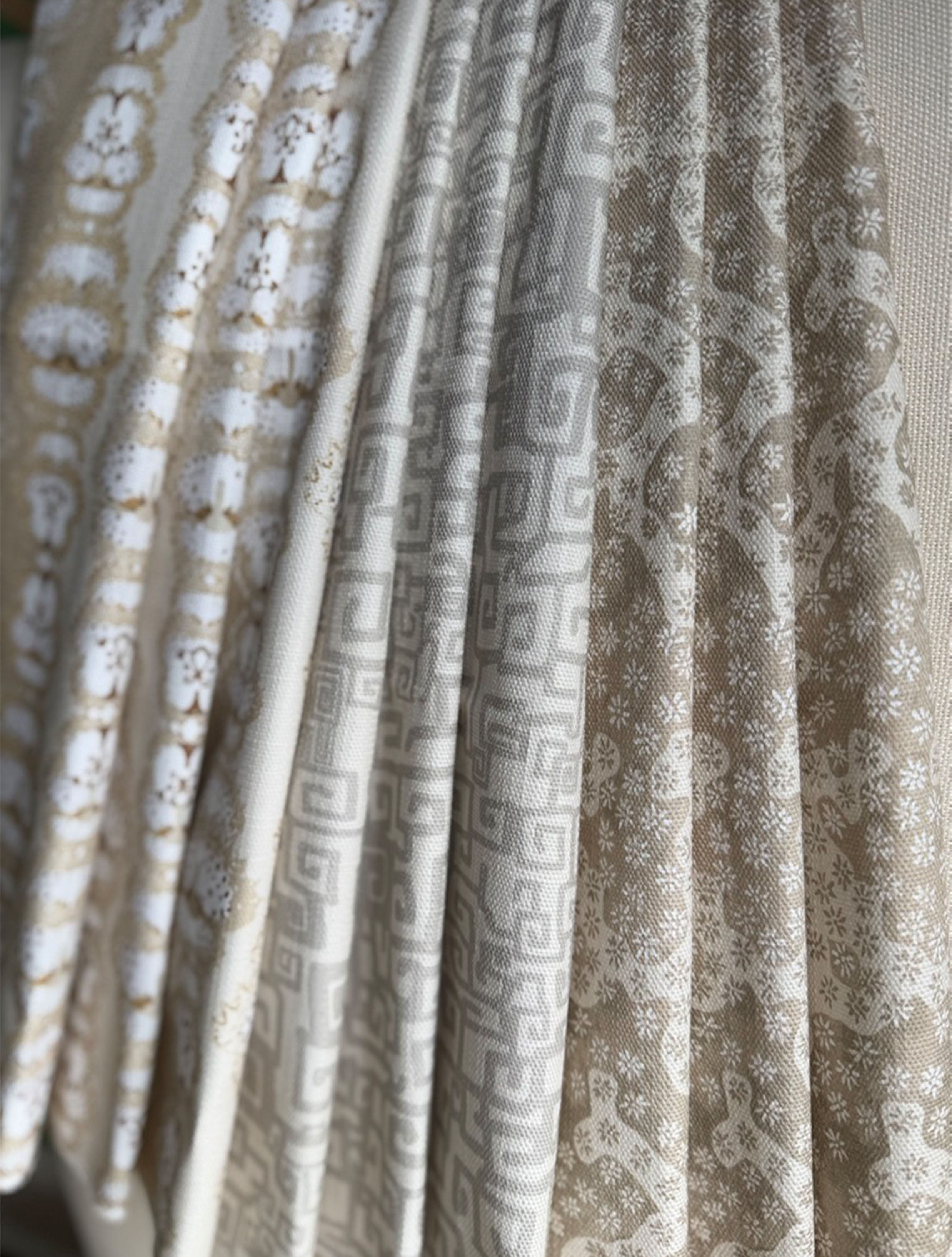 Stack of folded fabric swatches in various patterns in a soft neutral palette. 