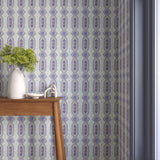 Interior with purple and blue geometric wallpaper and matching trim with a wooden console table with white ceramic vases with flowers. 