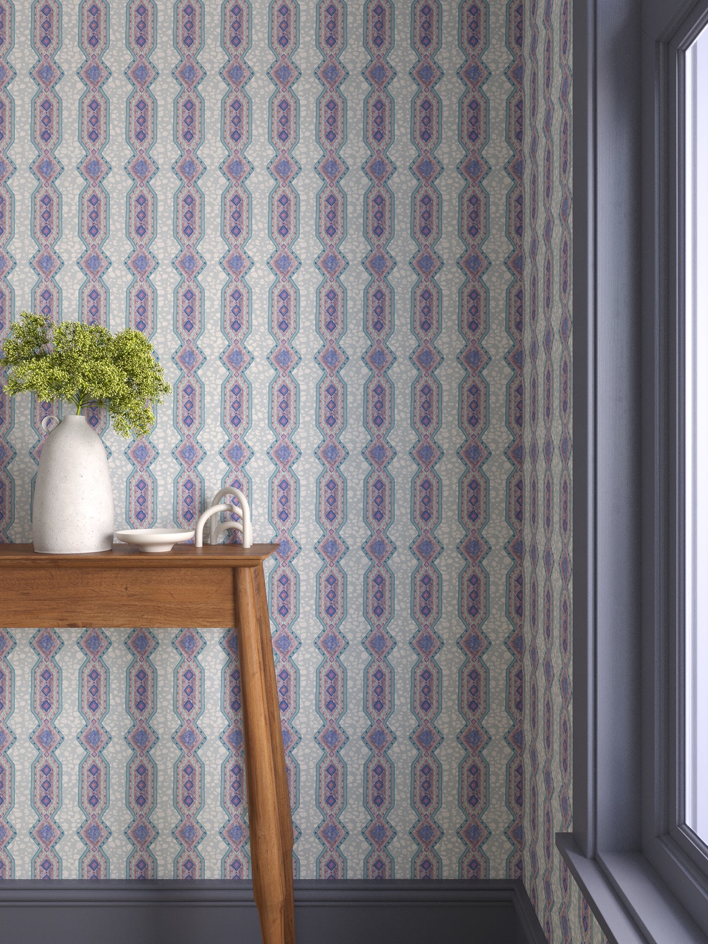 Interior with purple and blue geometric wallpaper and matching trim with a wooden console table with white ceramic vases with flowers. 