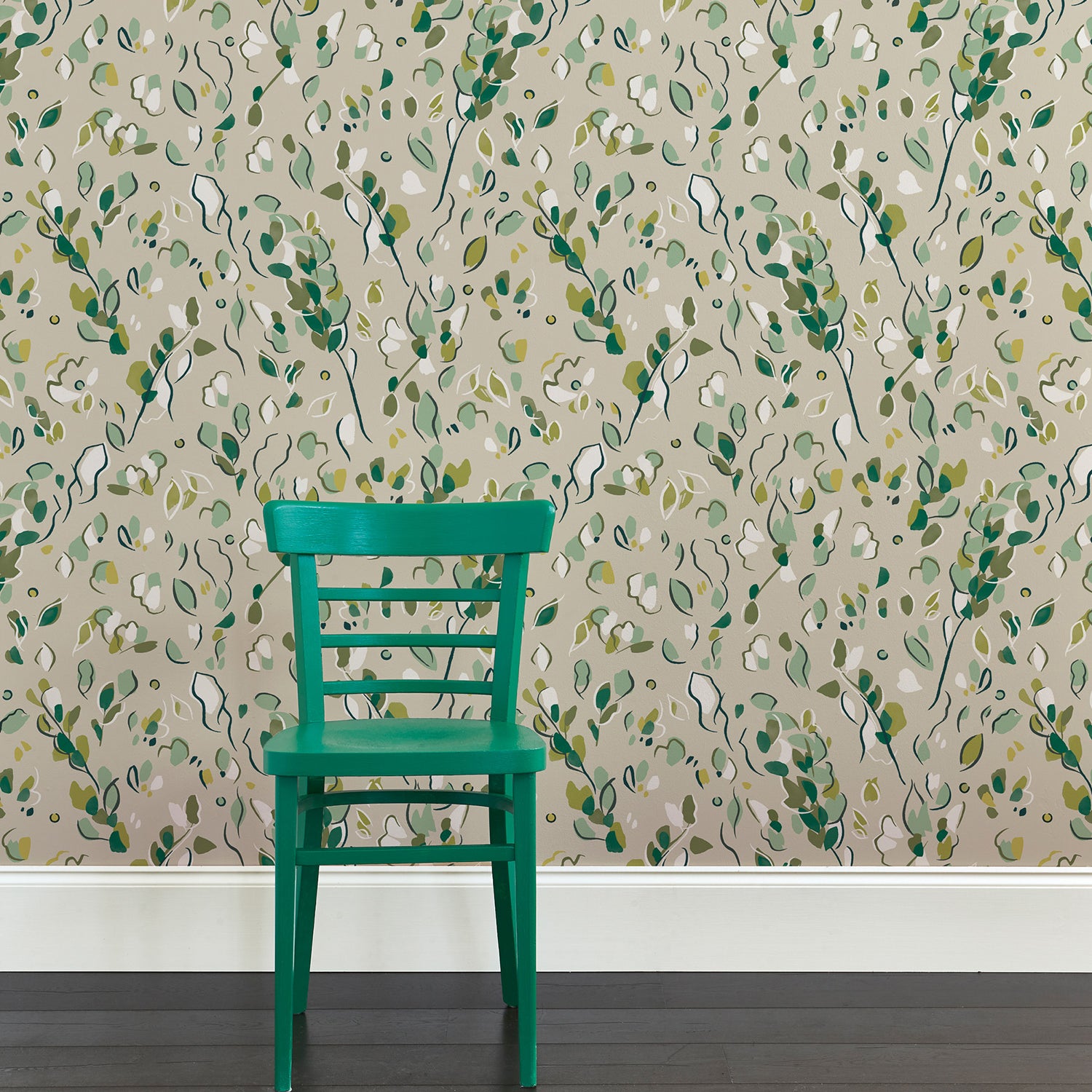 Green wooden chair against wallpaper in a painterly botanical design in shades of green on a tan field.