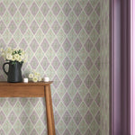 Interior with purple and green geometric wallpaper and matching trim with a wooden console table with black pitcher with white flowers and votive candles.  