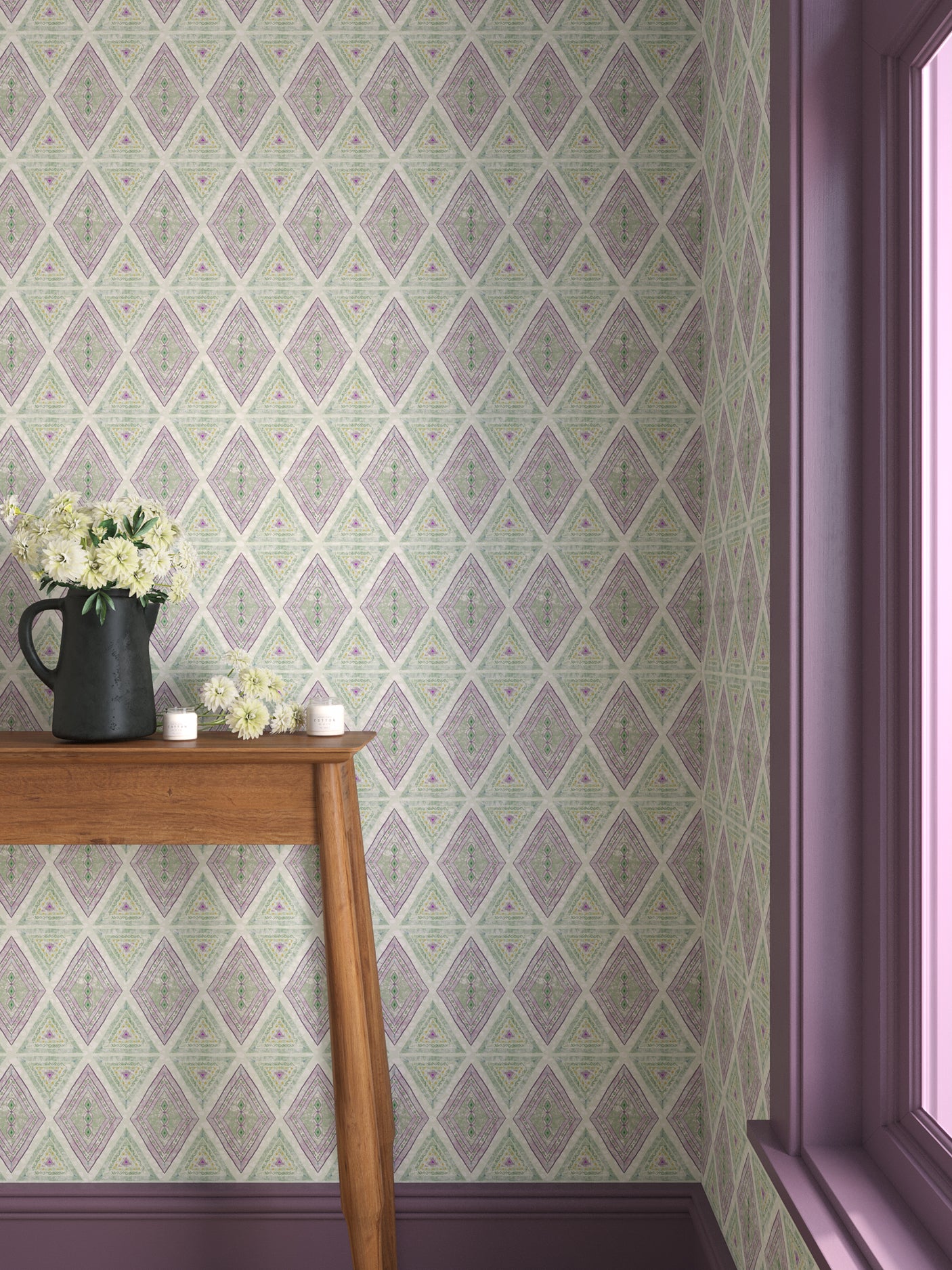 Interior with purple and green geometric wallpaper and matching trim with a wooden console table with black pitcher with white flowers and votive candles.  